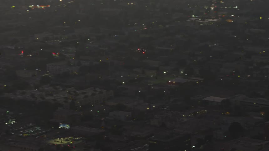 A helicopter flies by a skyscraper and over a large city