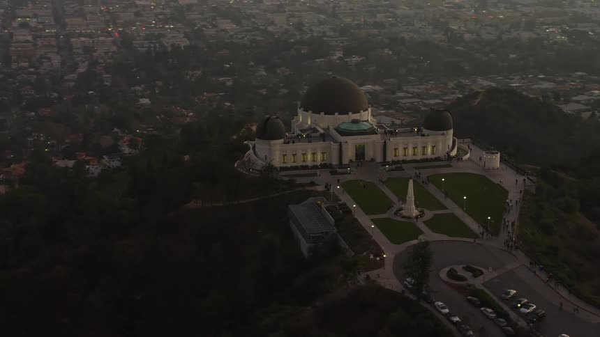 Aerial panorama of a palace with domes on the peak of a mountain in a morning orange sky