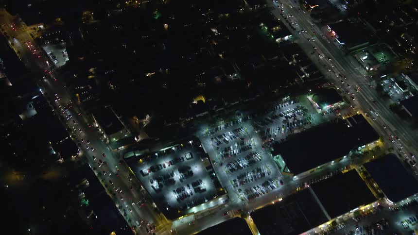 Aerial panorama of a city at night with illuminations of buildings houses and vehicle traffic