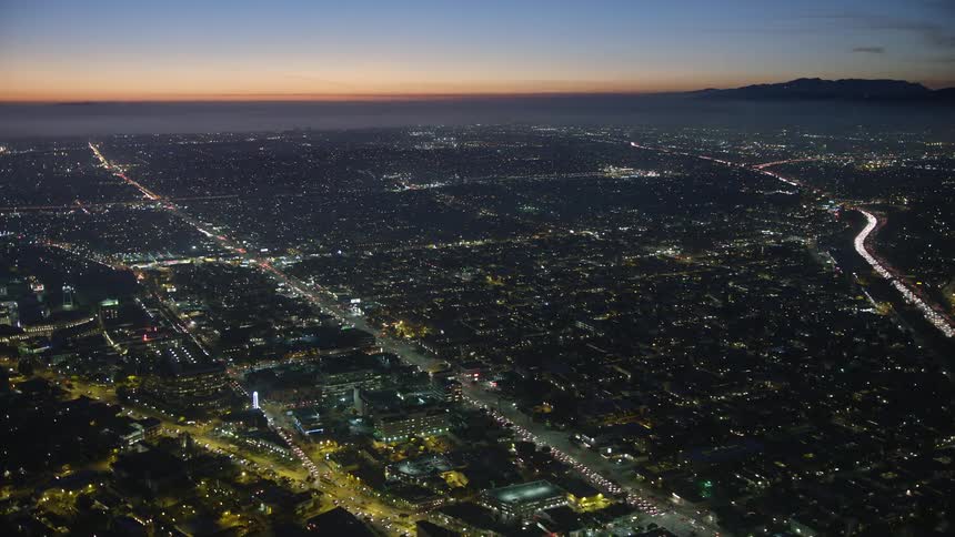 Aerial view of a city at dusk with lights illuminating the streets