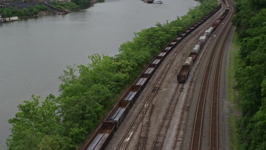 Aerial view of freight train tracks on the opposite site of a river to a large factory complex