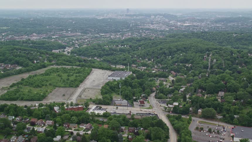 An aerial view of suburban homes and streets surrounded by green trees