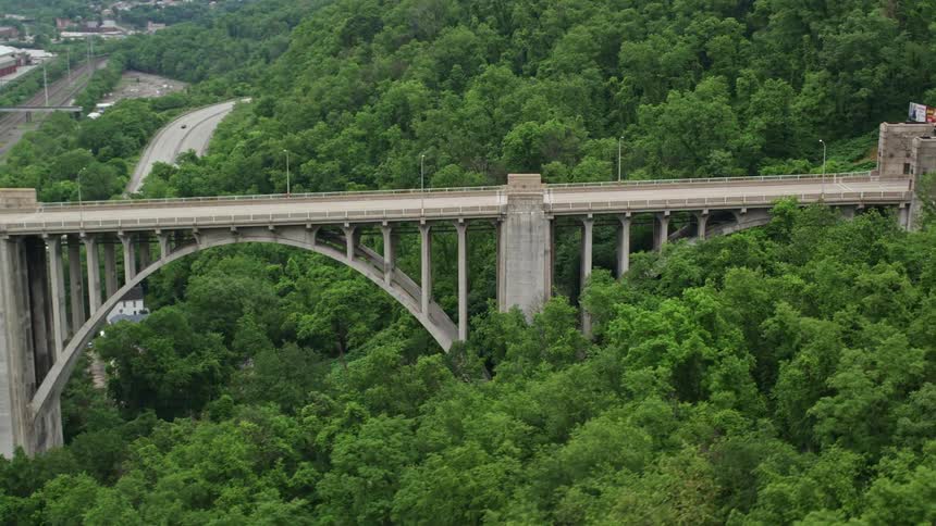 Aerial view of a huge bridge over a river and at a level of forested mountains