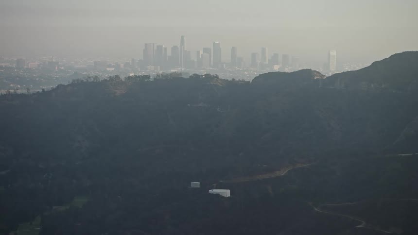 Aerial panorama of mountains with forests and skyscrapers in the background of a metropolis