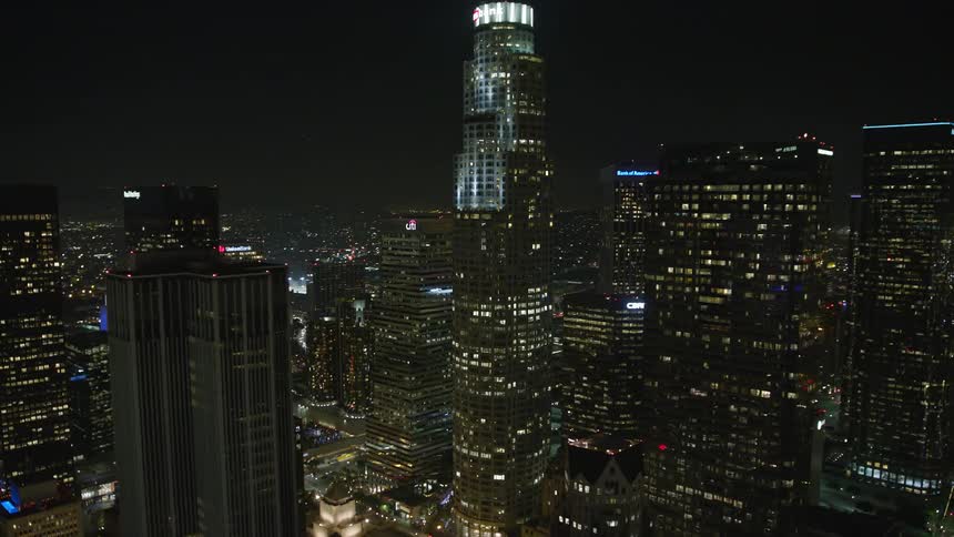 Skyscrapers loom over smaller buildings in the city at night