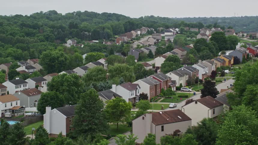Rows of houses on a hillside nestled between green trees