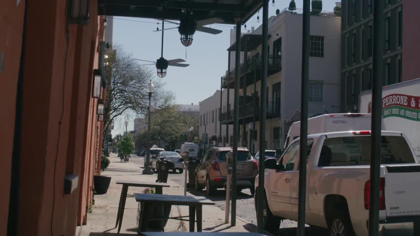 Street view from a sidewalk cafe with parked cars and buildings in the background