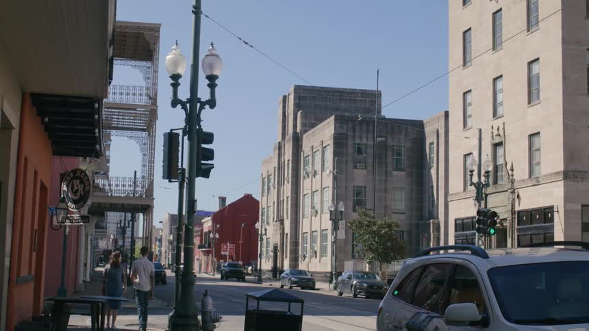 Street of a city with cars parked in urban and commercial buildings on a cloudless blue sky day