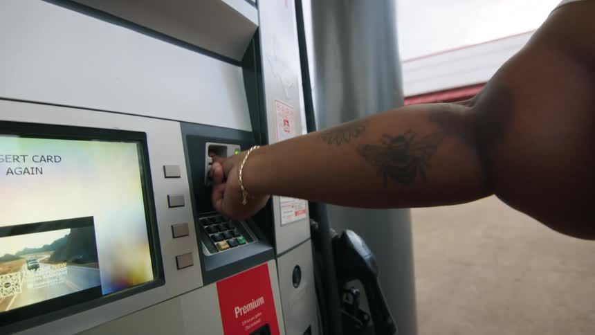 Woman inserts her credit card into the payment slot at the gas pump and removes it quickly