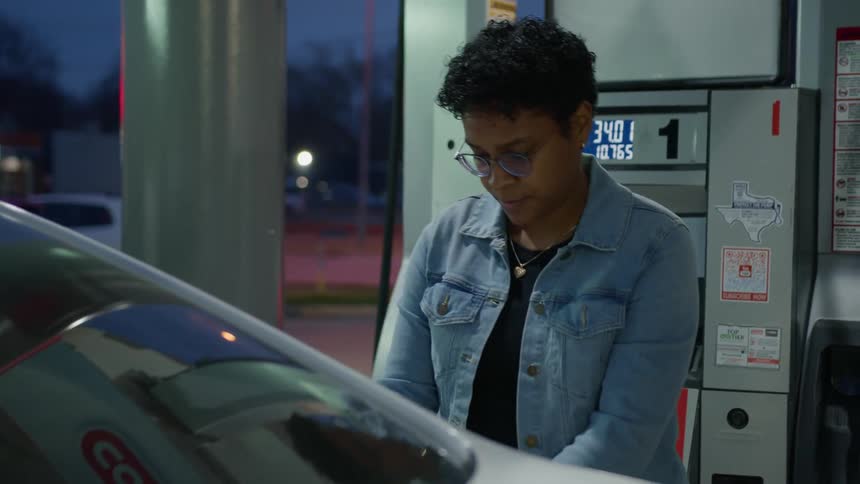 A woman is pumping gas at the gas station