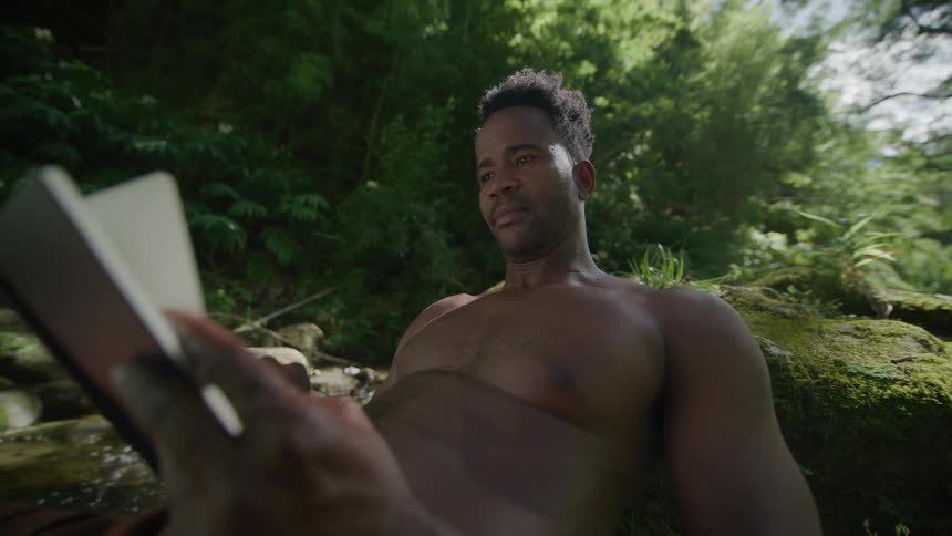 A man is sitting on the rocks reading