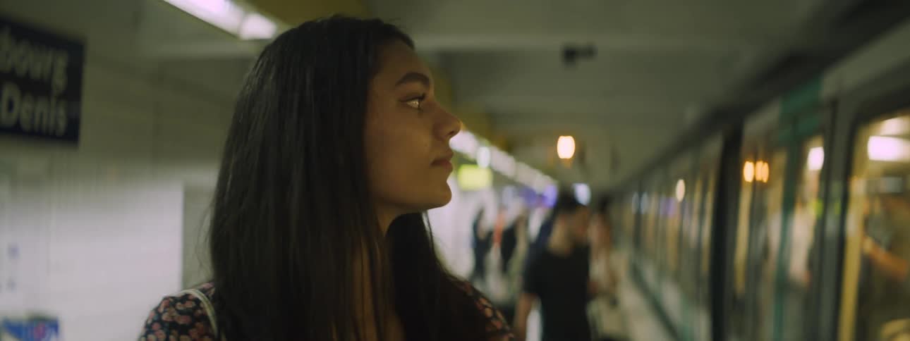 Portrait of a young woman at a station with a train arriving