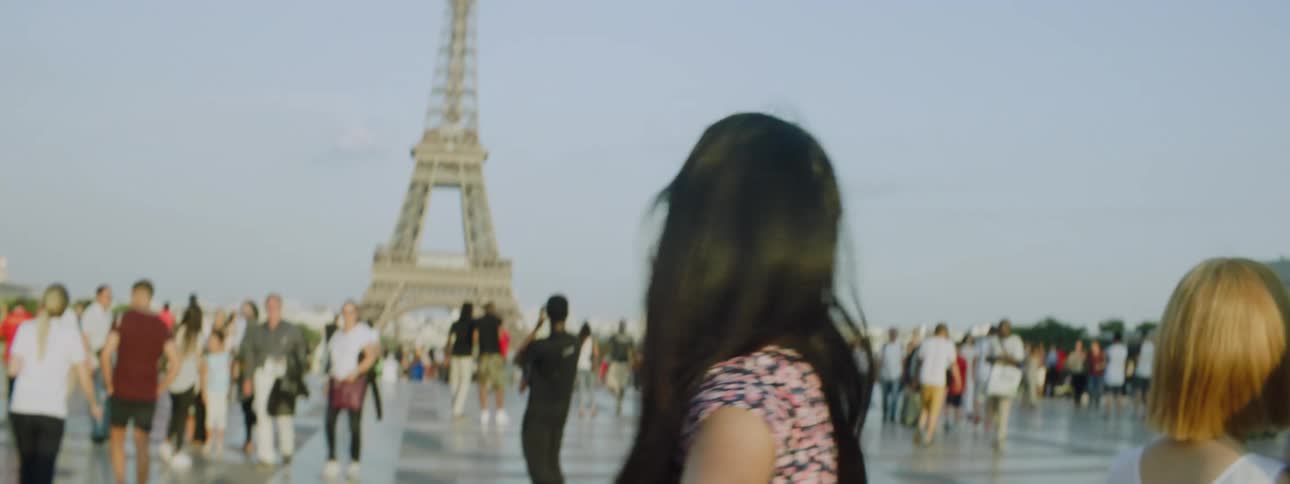 Portrait of a young woman in a crowd standing in the square in front of the eiffel tower