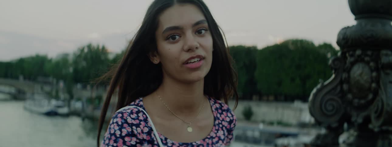 Young woman standing next to a river talks looking at the camera