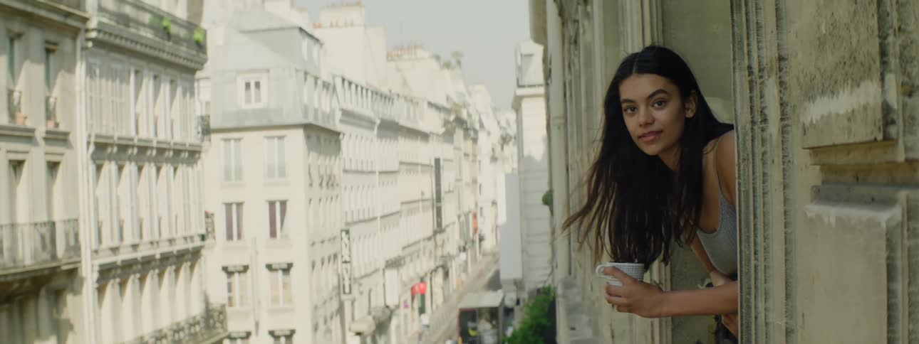 Young woman on the balcony of a building holding a mug