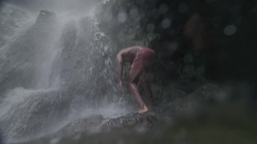 A clip of a man swimming at a waterfall
