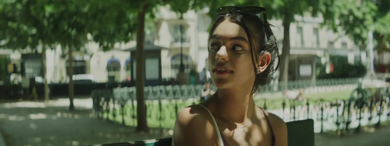 Young woman sitting in a city square and enjoying the view with a slight smile
