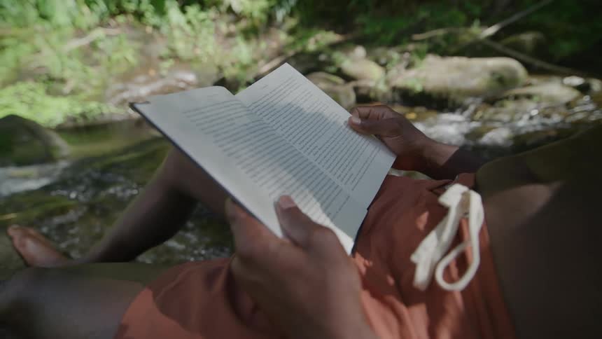 A clip of a person reading by the stream