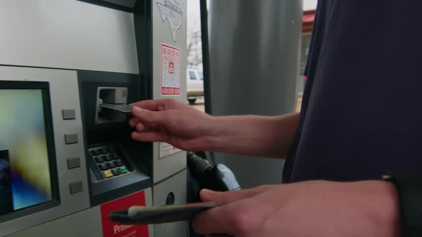 A man swipes his credit card at a gas pump