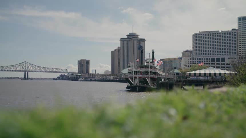 Tourist boat moored with buildings around in a metropolis and a bridge in the background on a blue sky day with clouds
