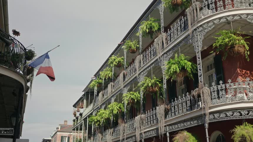 View of a building with balconies and balconies patterned with ferns on a blue sky day with clouds