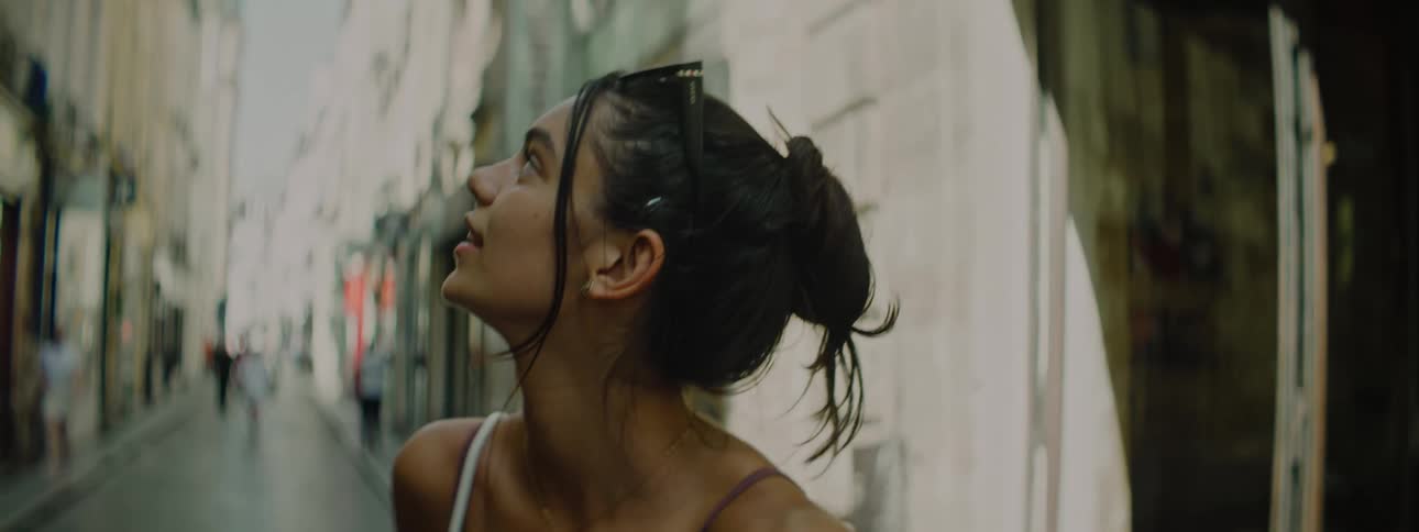 A young girl filming herself walking backwards on a street in the city