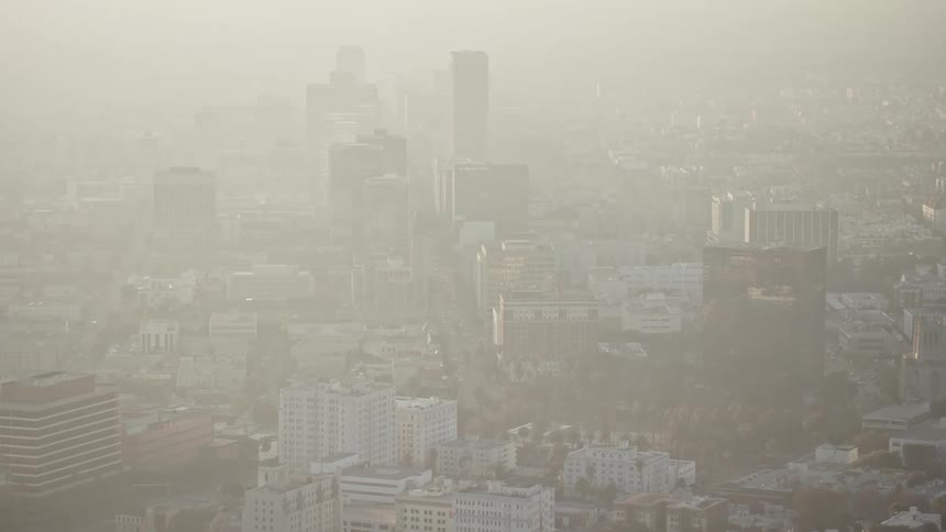 Aerial panorama of a metropolitan city with skyscrapers on a foggy day in the morning with sun flare