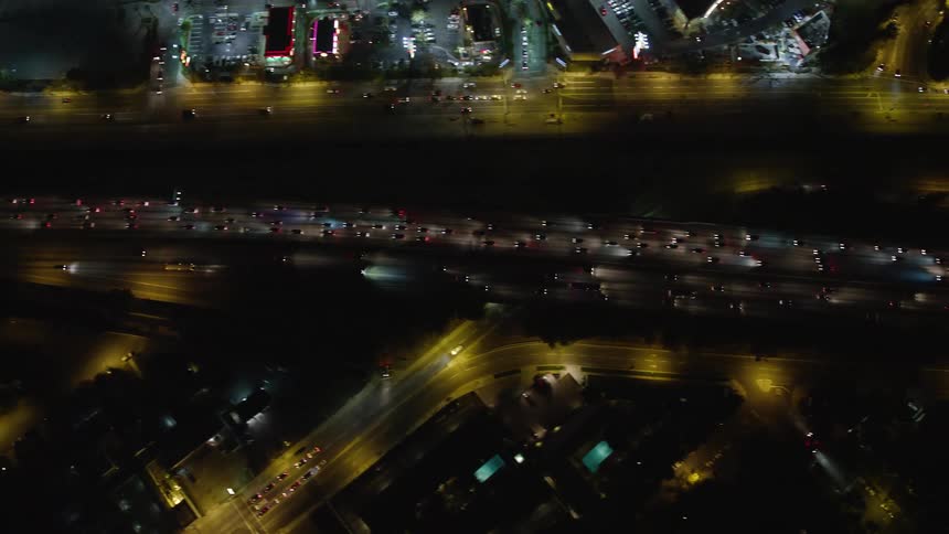 Aerial panorama of a highway and a half to a city with vehicle traffic at night