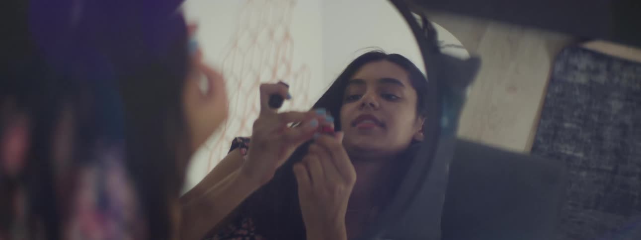 Close up of a young woman applying makeup in front of a mirror