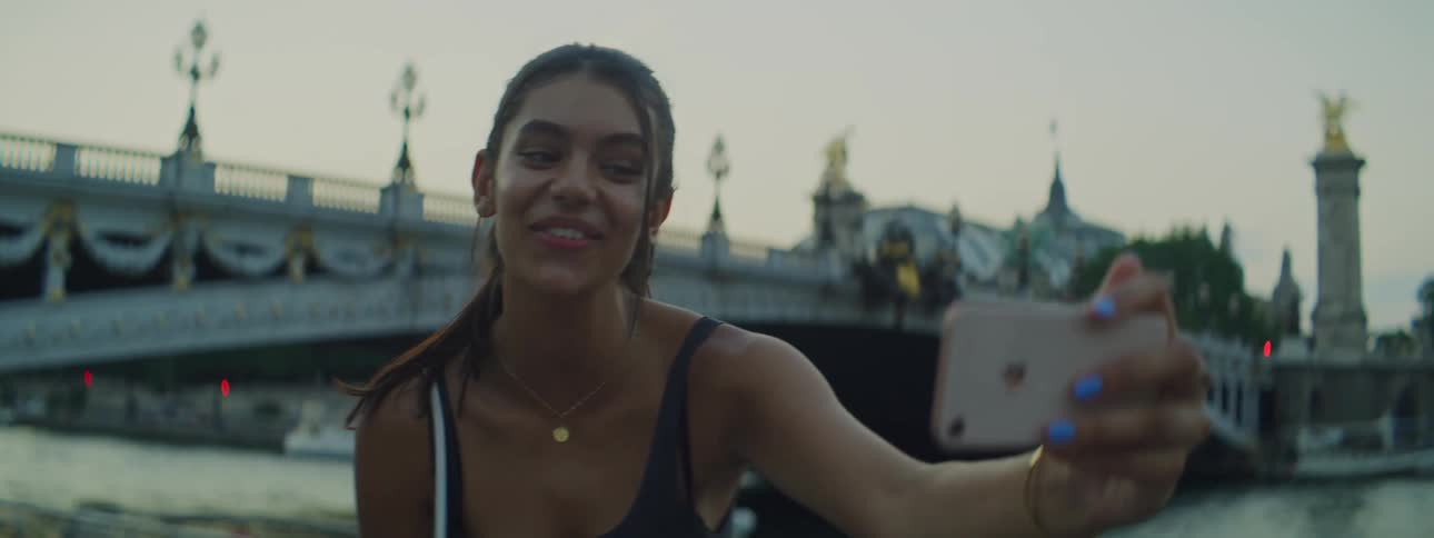 A happy girl films herself with a smartphone