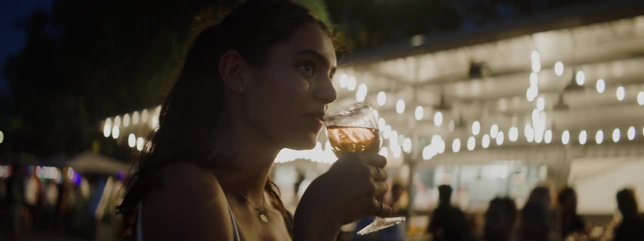 A teenage girl drinks an alcoholic drink at a gathering