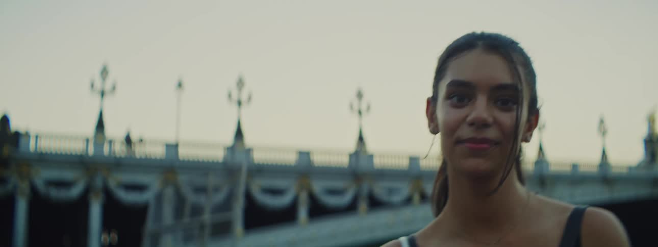 Portrait of a smiling young woman next to a bridge on a lake