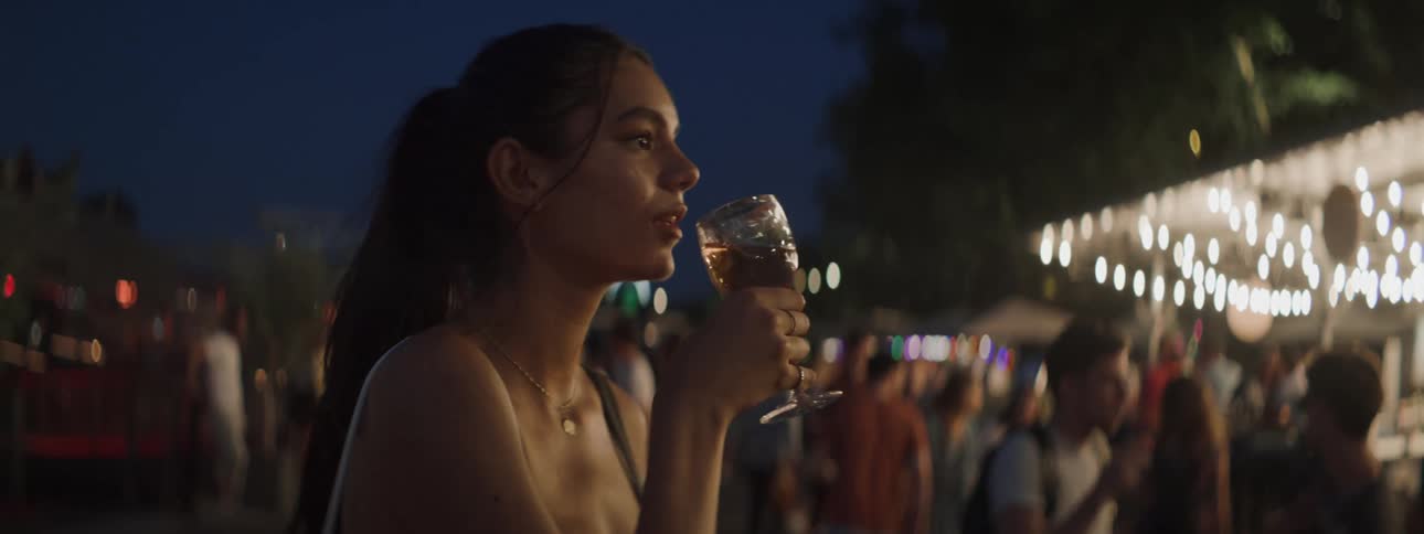Young woman drinking wine at a social event at night