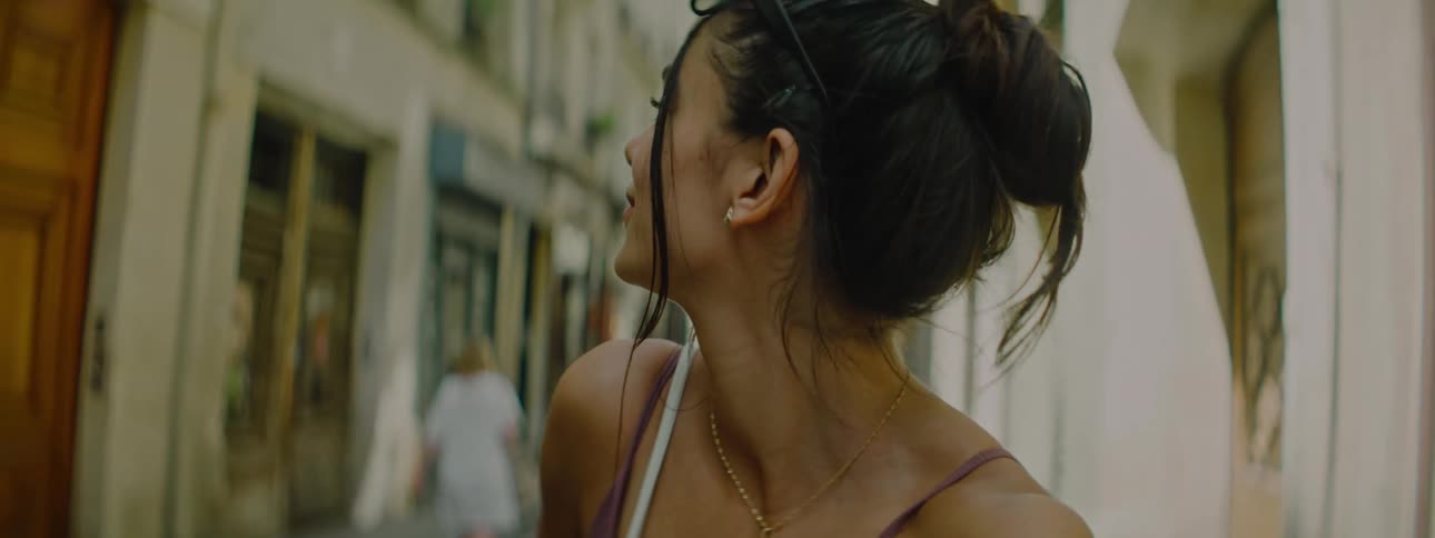 Portrait of a woman in selfie walking backwards through an alley in a city with shops