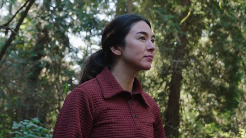 Young woman in the middle of a forest during the day observing