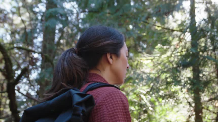 Woman carrying a backpack walking in the forest