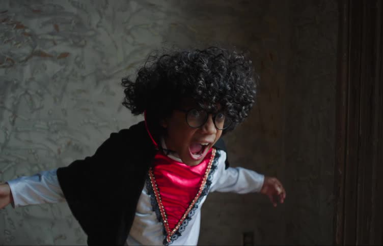 A boy wearing a black cape pretending hes a vampire