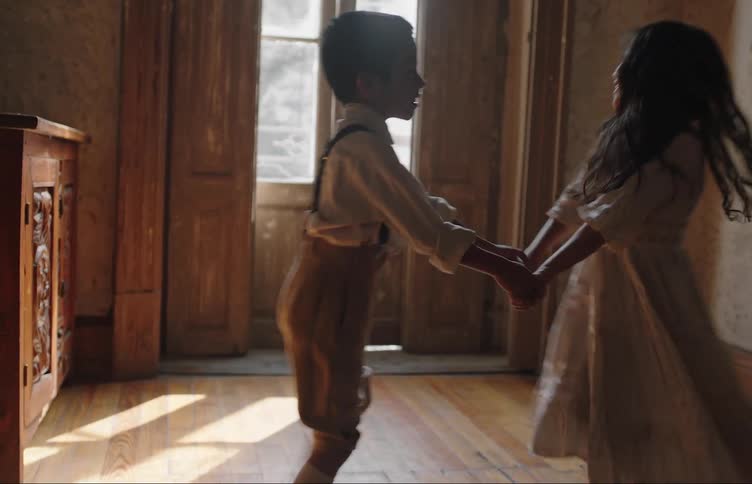 A boy and a little girl are dancing while holding hands and are spinning