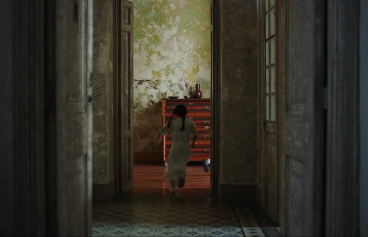 Two children playing running down the corridor of an old house