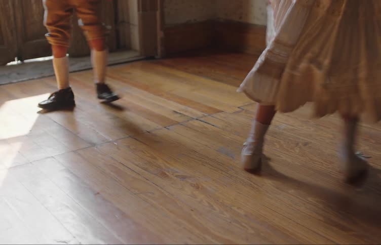 Boy and girl dance together near door in wooden floored room