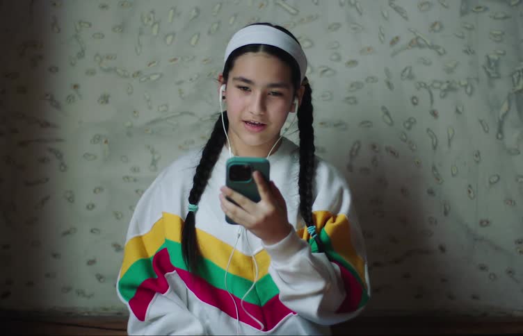 A teenage girl talks to someone through a smartphone