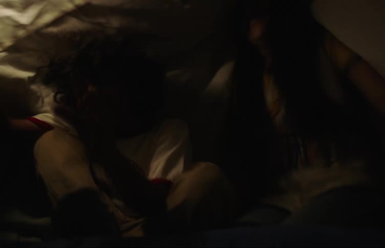 Two friends pretend they are in a very shaky situation under a sheet tent on the bed