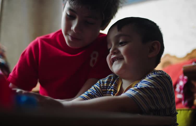 Brothers play with dinosaur toys together on a coffee table in the living room