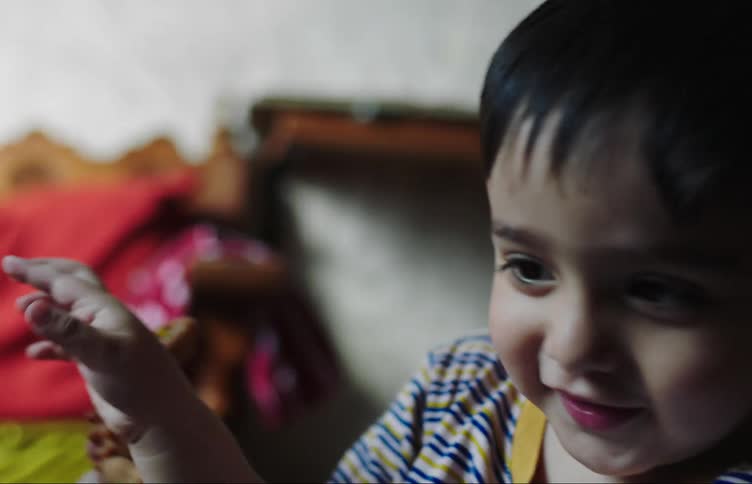 The face of a little boy who is talking and smiling while playing with toys