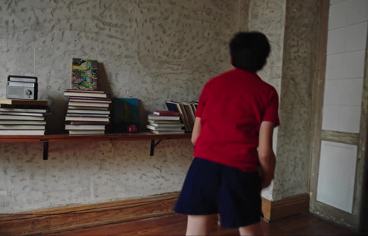 Boy with a soccer ball playing against the wall of the house with his hands