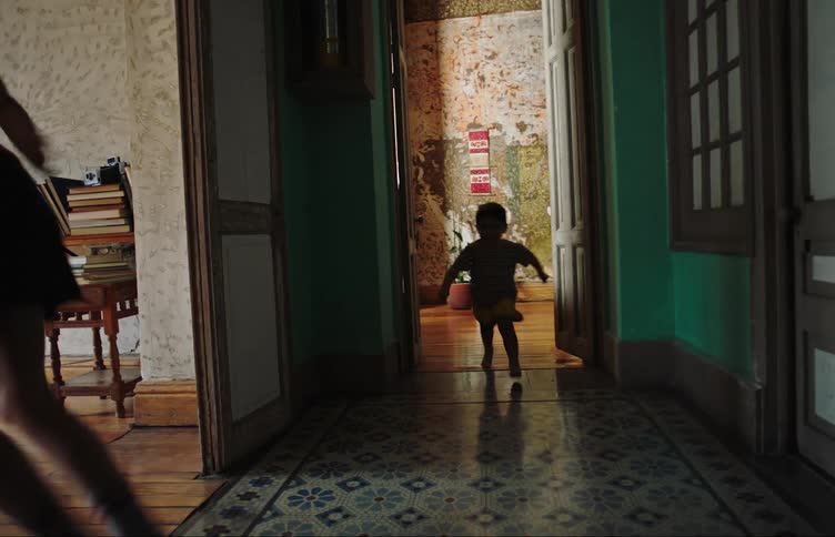 Two children running indoors with a soccer ball