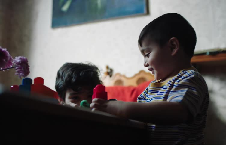 Two boys playing with plastic blocks at home
