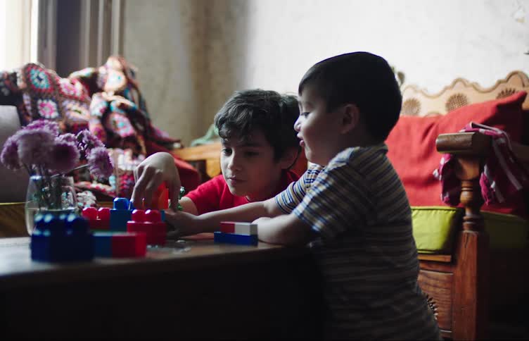 Two boys playing with plastic blocks at home