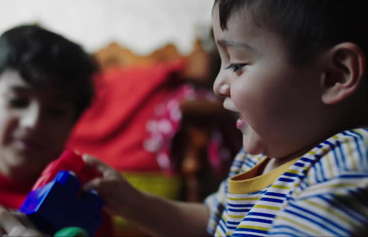 Portrait of two little boys playing and assembling plastic parts in the room