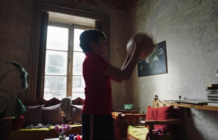 Boy indoors with a soccer ball throwing against the wall